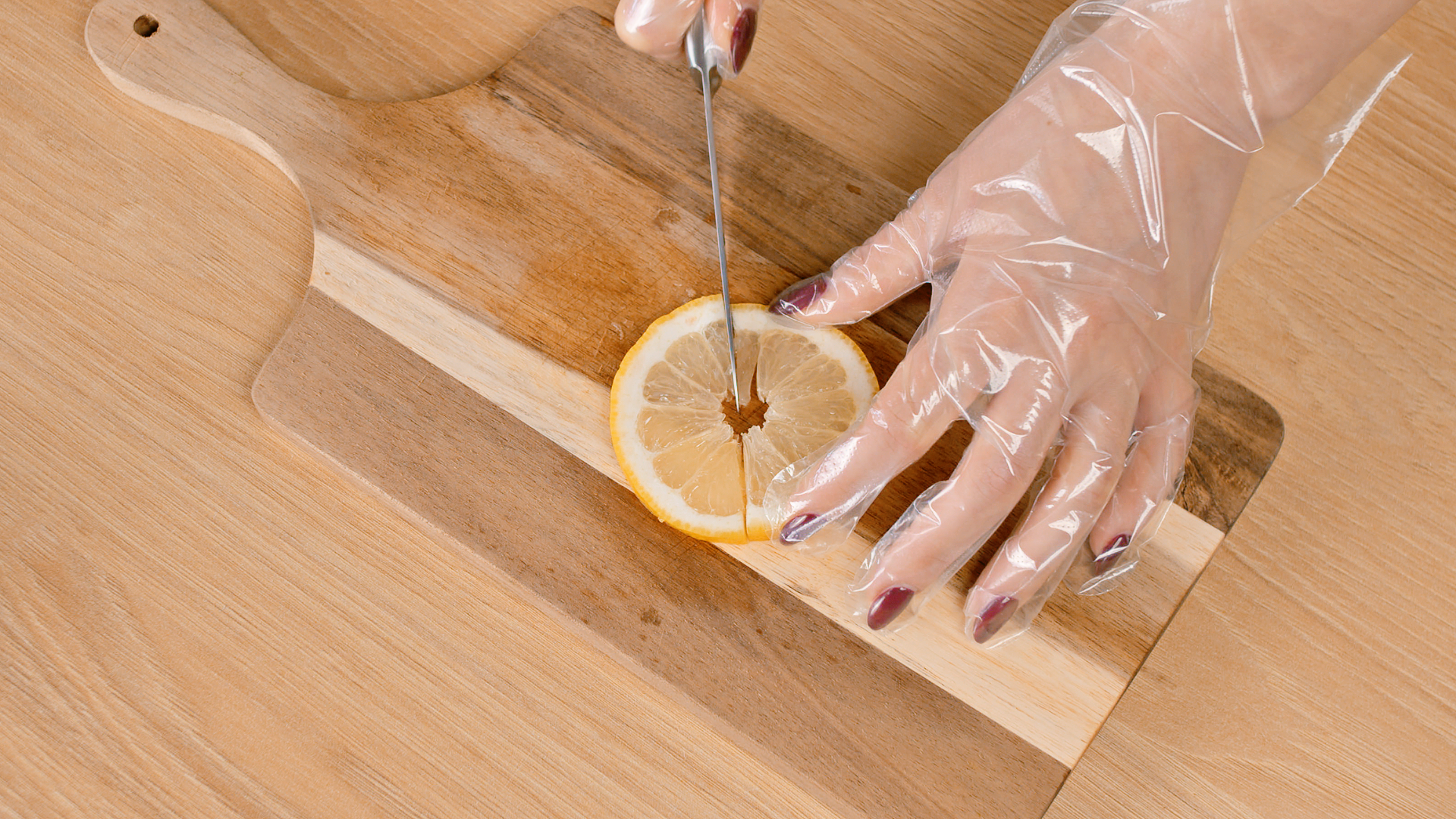 Hands with disposable gloves cutting orange